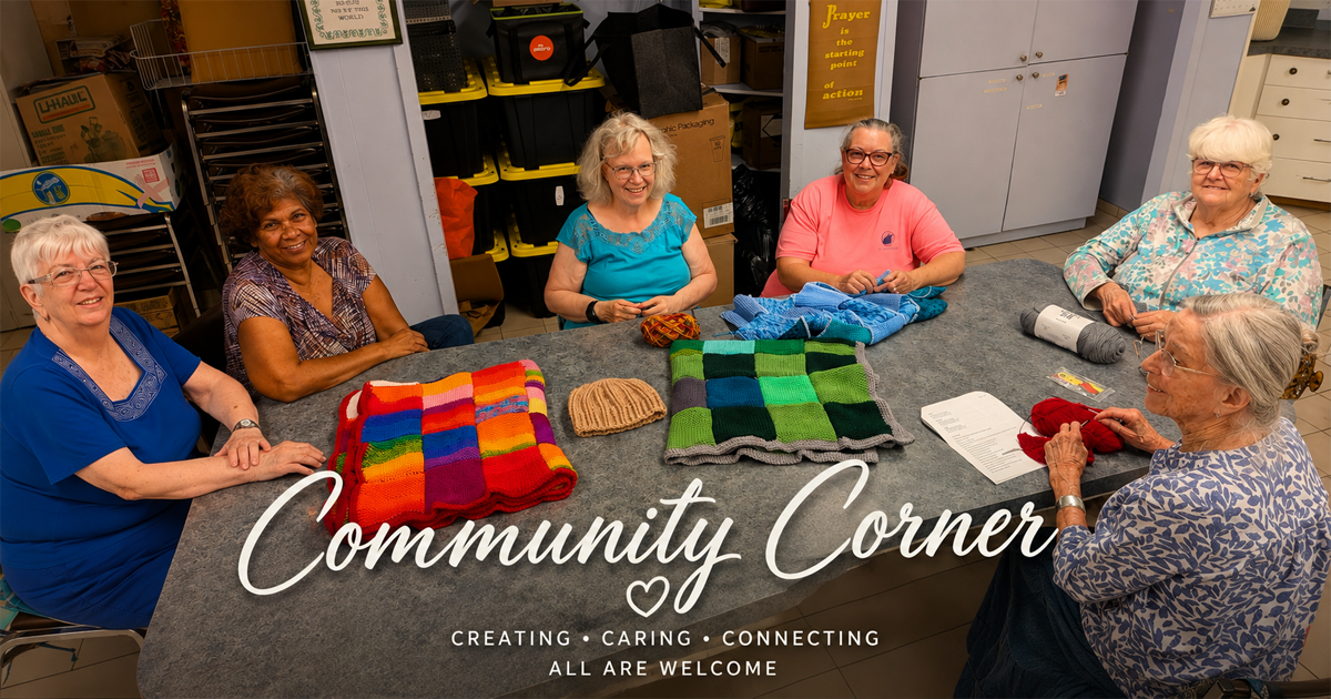 Members of Community Corner gathered around a table with colourful handmade knitting and crochet projects